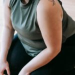Taking Breaks - Overweight woman sitting on floor in gym near battle ropes