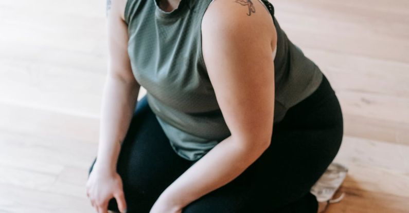 Taking Breaks - Overweight woman sitting on floor in gym near battle ropes