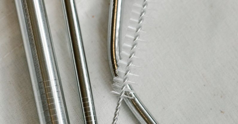 Sustainable Supply - Top view composition of stainless steel straws and brush arranged on white bag on table