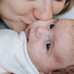 Embracing Change - Smiling mother kissing cute infant with closed eyes